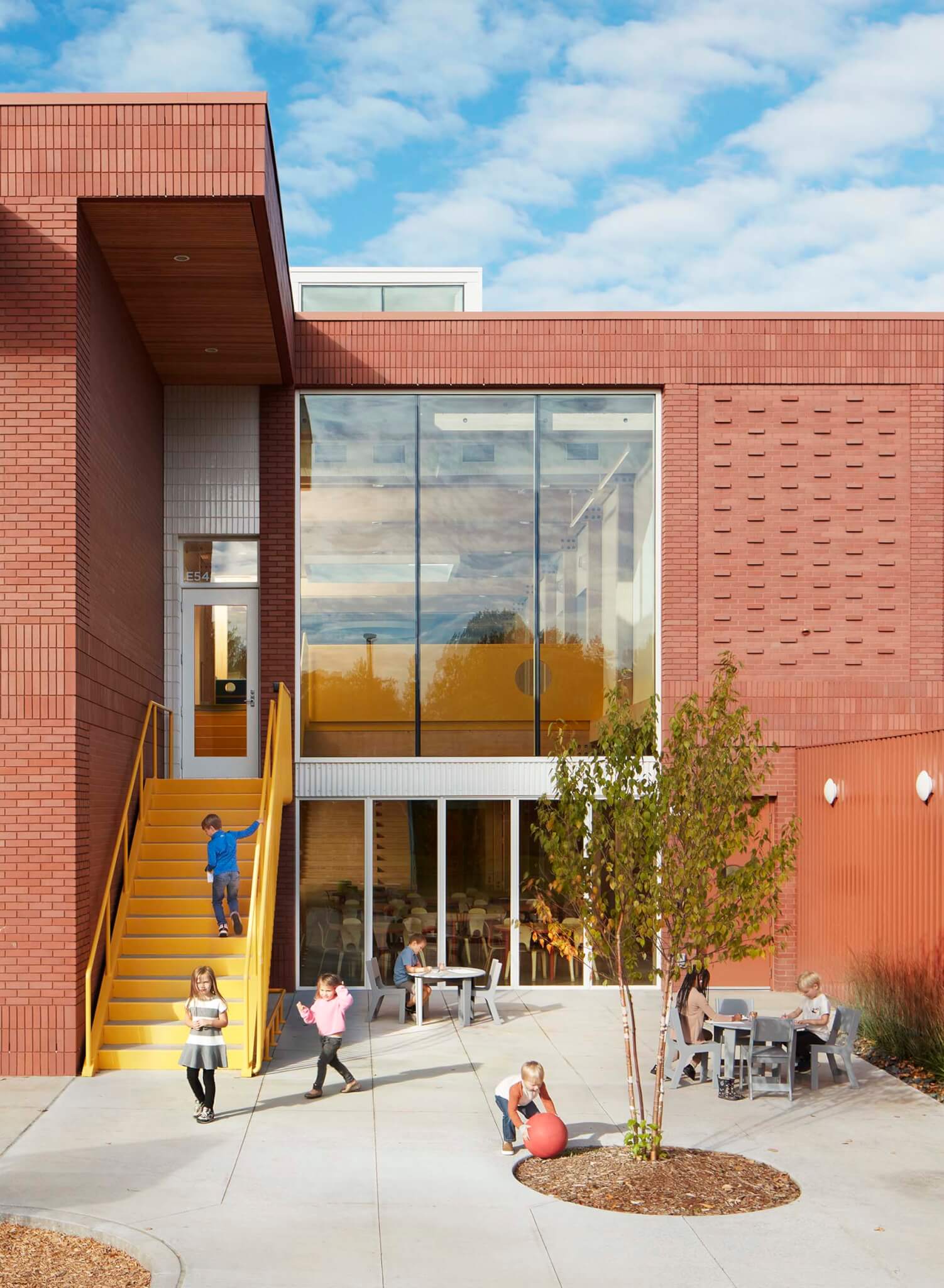 kids playing outside brick building with yellow staicase