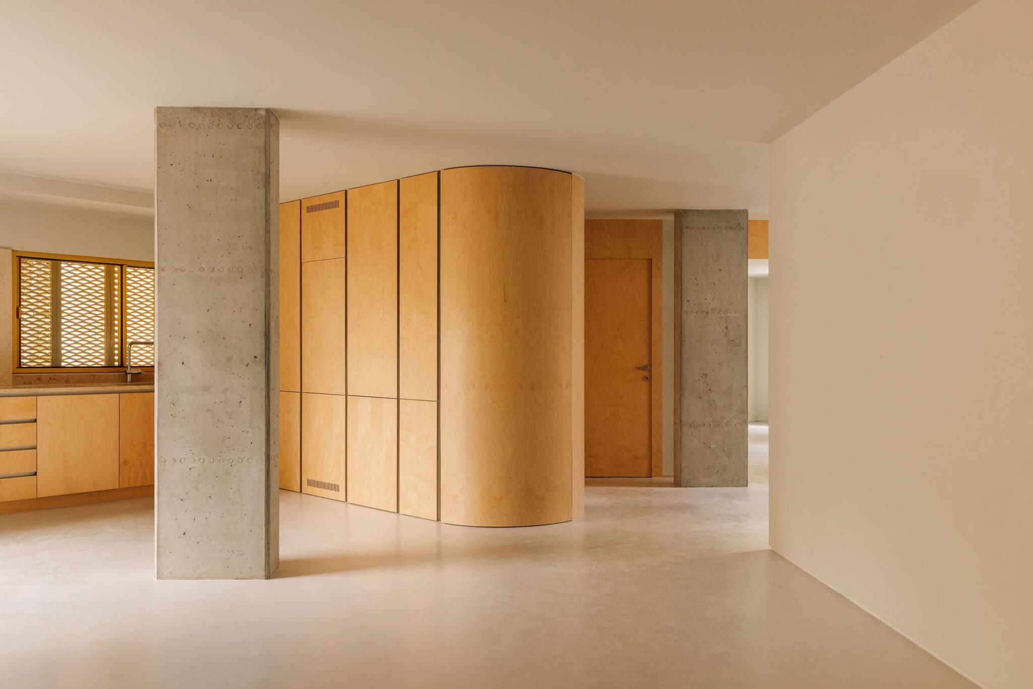 The interior of the apartment features epoxy floors, exposed concrete structure, and birch furnishing